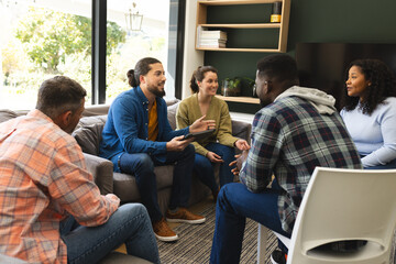 Diverse group of friends and male therapist with tablet in group therapy session