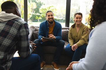 Diverse group of friends and male therapist with tablet in group therapy session