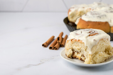 Fresh Cinnabon rolls with cinnamon and white cheese cream, horizontal, free space for inscription, on a light background, close up..