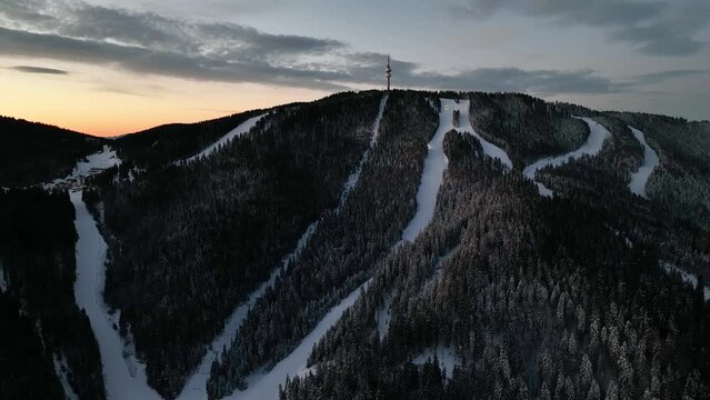 4K Aerial winter sunrise or sunset view of Rhodope Mountains and Snezhanka tower near resort of Pamporovo, Smolyan Region, Bulgaria. Holiday winter shot