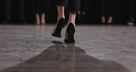 Follow cam shot of stepfoot of girl heels on defile catwalk. Legs attractive woman in model show fashion on catwalk closeup. Models walk on podium. Slender legs on thin high black stilettos