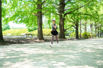 Active young Asian sportswoman running in a green park outdoors with sunlight in the morning. Health and fitness training, healthy living lifestyle