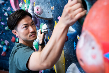 Young man enjoying climbing at bouldering gym. Close-up. Selected focas. Healthy lifestyle and well-being.