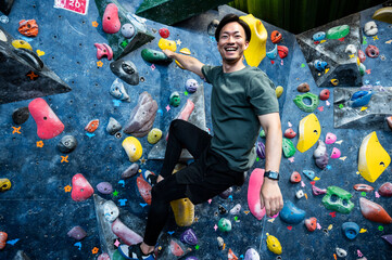 Young man enjoying climbing at bouldering gym	