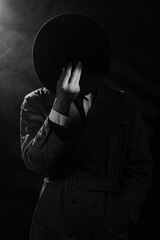 a dark silhouette of a man in a raincoat and a hat in the style of crime noir. Dramatic noir...