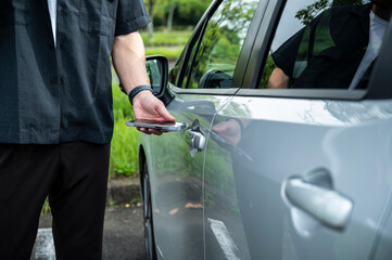 Young Asian man using mobile app device on a smartphone to unlock the doors of his intelligence car.