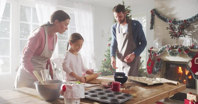 Happy Family During Christmas: Slow Motion Portrait of Little Cute Girl Learning How to Make Cookies and Celebrating her Achievement with her Parents. Cute Family Preparing Together for Holiday Dinner