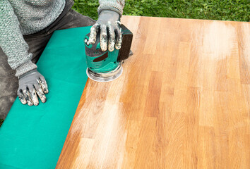 Close up view of person working with sander tool, sanding off stains on old damaged butcher block...