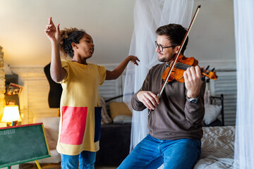 Fototapeta Young father teaching his adopted daughter to play violin. Single parent child happiness concept. obraz
