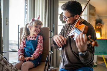 Fototapeta Charming little girl learning to play the violin with an artistic music teacher. obraz