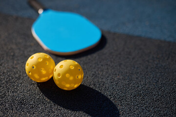 Perforated balls and racket for pickleball on the court ground with empty space for text