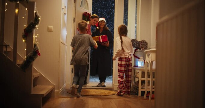 Family Celebrating Winter Holidays Together. Small Son and Daughter Meeting Grandmother, Who Just Arrived with Festive Holiday Gifts. Grandparent Visiting Family for Christmas and New Year
