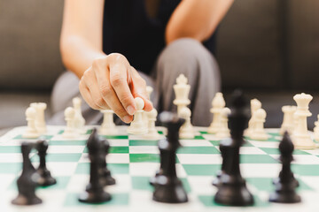 Woman playing chess board game at home.