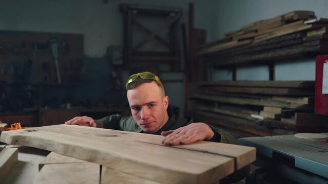 A focused carpenter in the carpenter checks the quality of the wood product. Joinery, small business.