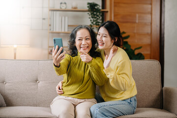 Happy adult granddaughter and senior grandmother having fun enjoying talk sit on sofa in living room at home.