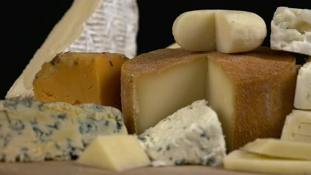 Close up low angle narrow focus cheese assortment rotating on board