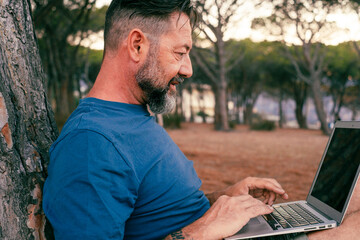 One modern adult man using and working on laptop at the park. Concept of smart working and...