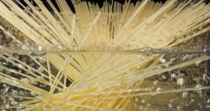 Cooking pasta spaghetti. Chef throwing raw spaghetti into boiling water in pot on kitchen stove. Italian cuisine, food preparation, cook blog. View from the side