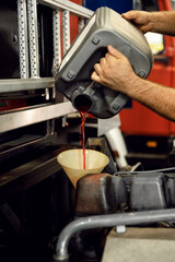 Changing the oil in the engine box of a fire truck. service of a company car. car service problem with the engine. the technician fills in new oil