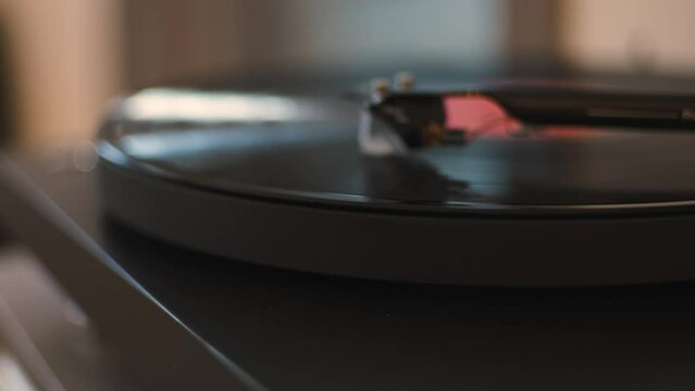 A vinyl record spins in the gramophone music player and plays an old disco. Close-up shot of modern vinyl turntable player with carbon tonearm
