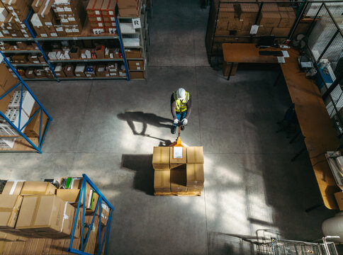 Top view of a warehouse worker pushing a pallet jack