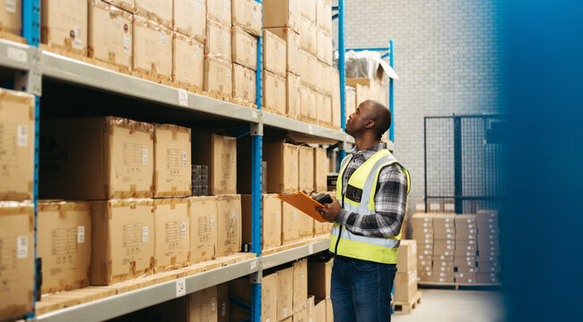 Male warehouse worker doing stock control in a logistics centre