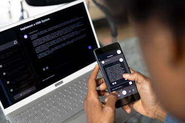 African american casual businessman laptop and holding smartphone with web chat on screen