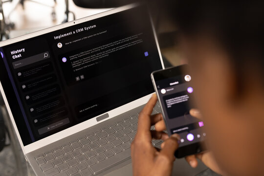 African american casual businessman laptop and holding smartphone with web chat on screen