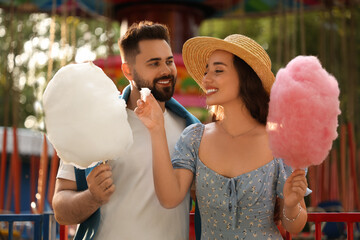 Happy couple with cotton candies at funfair