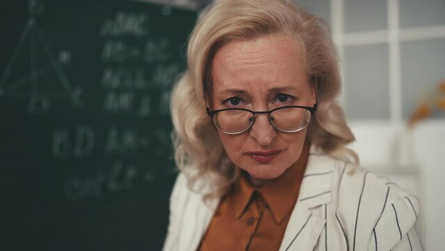 Strict geometry teacher attentively looking at camera, displeased with behavior
