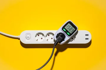Foto op Aluminium Top view auf ein Energiekosten Messgerät in einer Steckerleiste vor gelbem Hintergrund © Robert Poorten