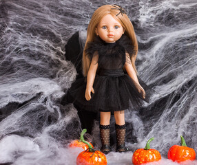  Plastic doll toy in a witch costume and decorative pumpkins, Halloween decor, selective focus