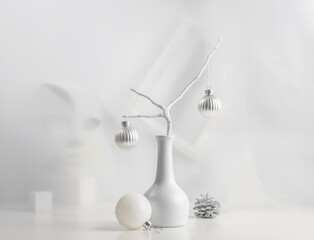 Monochrome Christmas still life: pine branch in a white vase, Christmas decorations, abstract