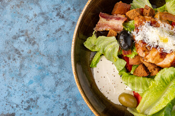 Caesar Salad on blue gray stone background, top view, copy space. chicken caesar salad with grilled croutons.