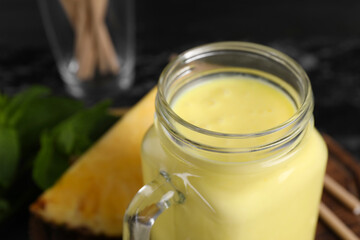 Tasty pineapple smoothie in mason jar, closeup. Space for text