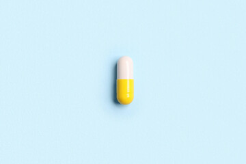 Fototapeta na wymiar One pill on light blue background, top view