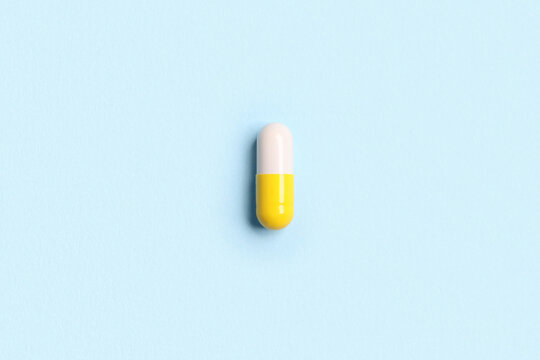 One pill on light blue background, top view