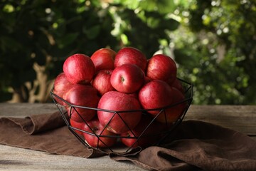 Ripe red apples in bowl on wooden table outdoors