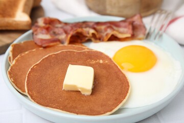 Tasty pancakes served with fried egg and bacon on white tiled table, closeup