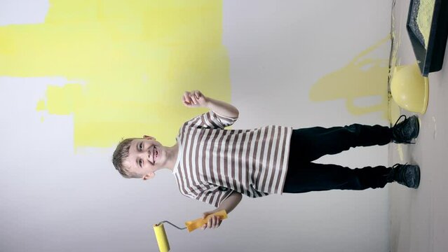 Cute boy with a paint roller. Happy kid helps parents to paint wall. Home renovation.