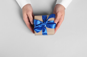 Man holding gift box with blue bow on white background, top view. Space for text