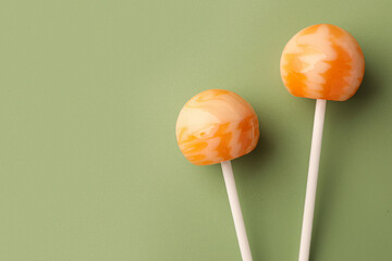 Tasty lollipops on green background, flat lay. Space for text
