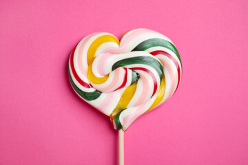 Stick with heart shaped lollipop on pink background, top view