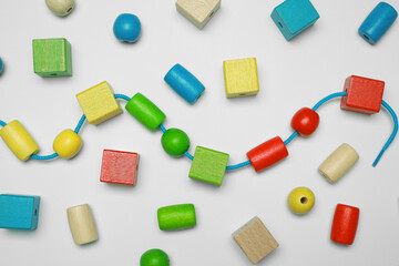 Wooden pieces and string for threading activity isolated on white, top view. Educational toy for...
