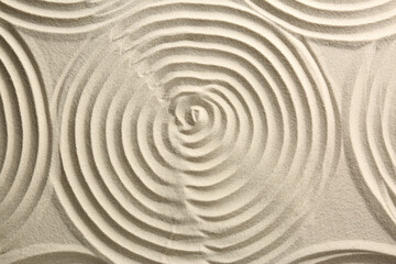 Fototapeta na wymiar Beautiful spirals on sand, top view. Zen garden