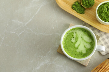 Cup of fresh matcha latte and green powder on light grey marble table, flat lay. Space for text