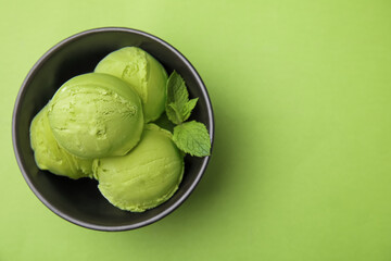 Tasty matcha ice cream in bowl on green table, top view. Space for text
