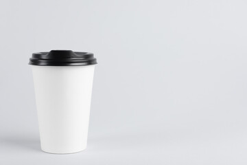 Paper cup with plastic lid on light background, space for text. Coffee to go