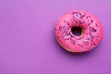 Sweet glazed donut decorated with sprinkles on purple background, top view and space for text....