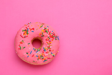 Sweet glazed donut decorated with sprinkles on pink background, top view and space for text. Tasty...